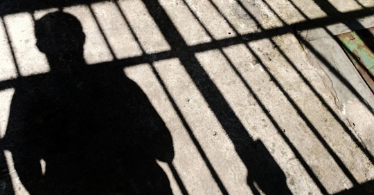 silhouette of a person behind bars
