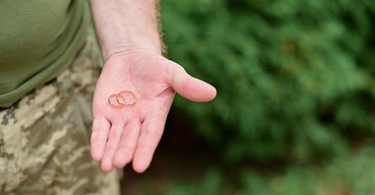 military man holding wedding rings