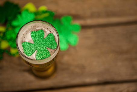 Beer glass with a glittery green shamrock on the foam, symbolizing Fake Patty’s Day drinking celebrations in Aggieville, Manhattan, Kansas.