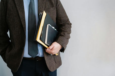 a guy in a suit holding a notepad and folder
